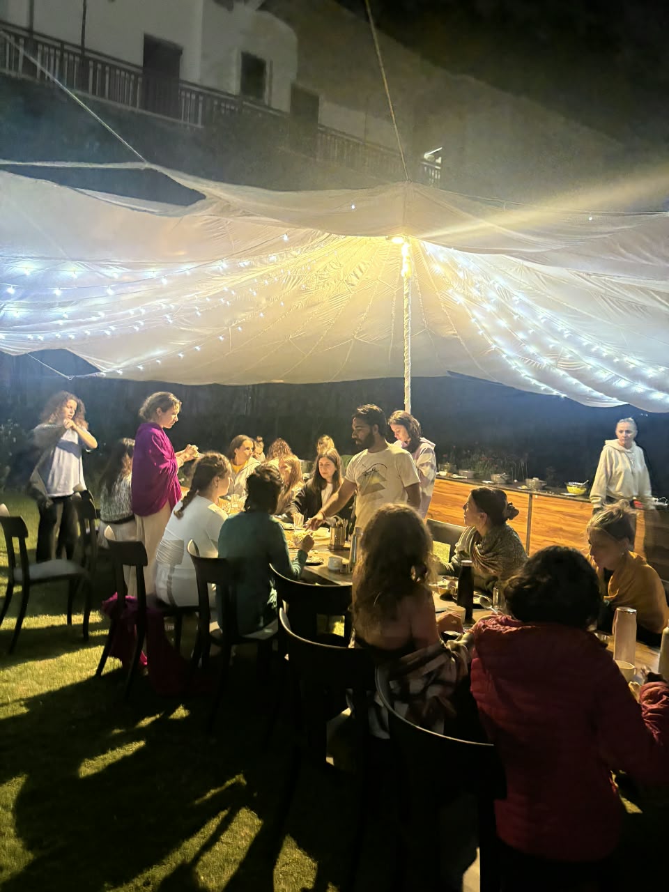 The group gathered for dinner under a lit tent in the evening