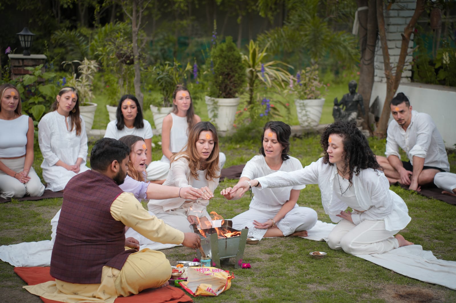 Pradeep leading a group fire ceremony, guests in white gathered around the flame