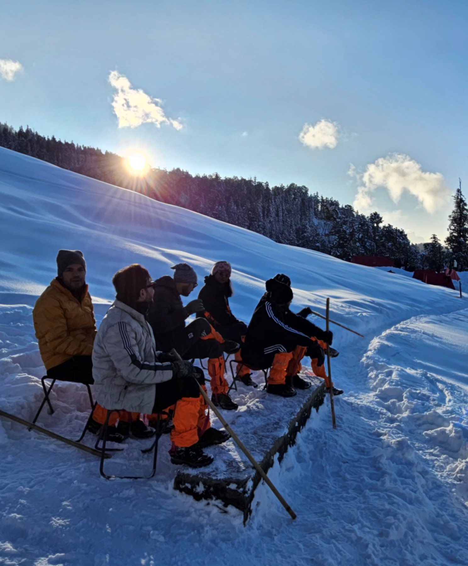 The group sitting out together on the snow as the sun rises over the ridge