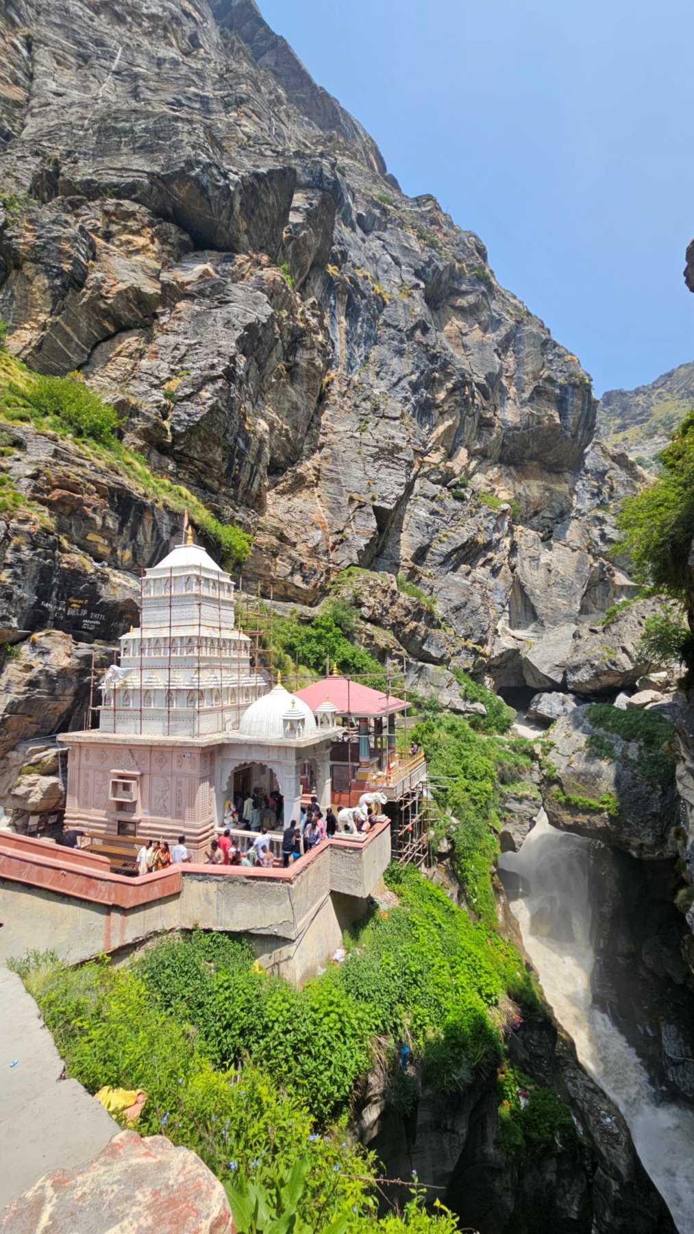 A white marble shrine set into a gorge wall above rushing water