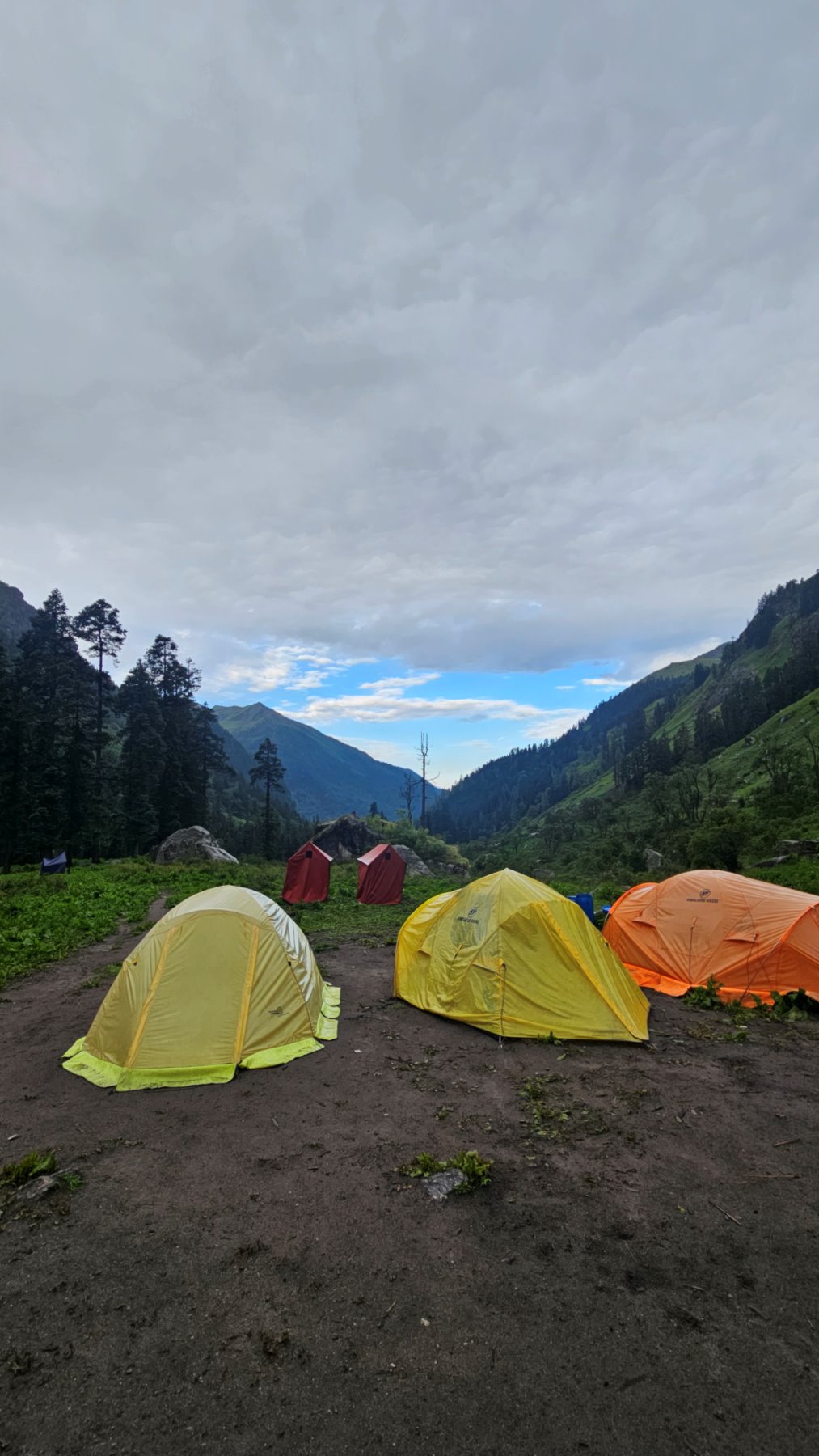 Tents pitched in a green Garhwal valley under an evening sky