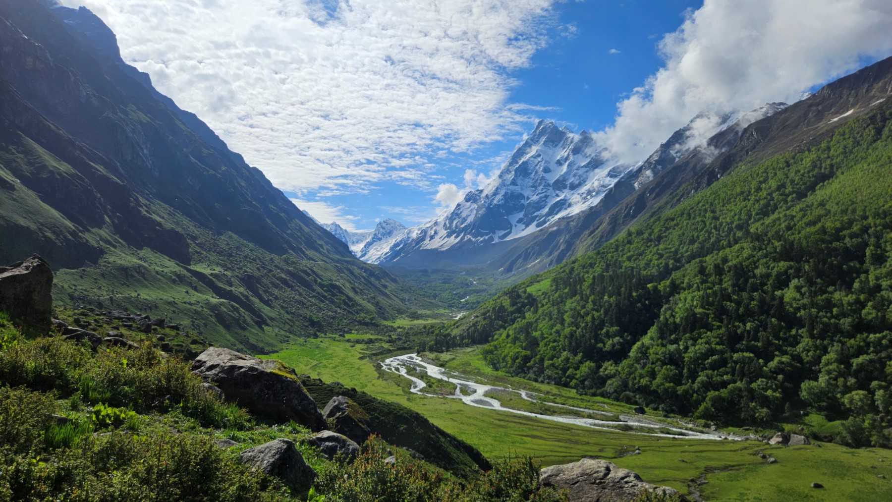 A glacial river winding through the green Har Ki Dun valley below snow-capped Himalayan peaks
