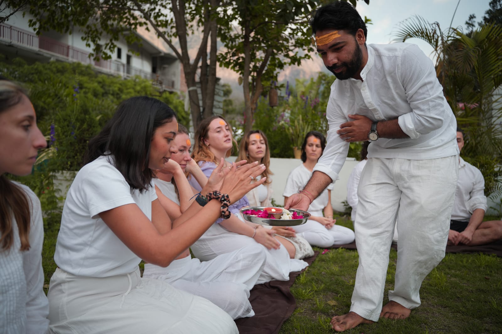Pradeep offering a flower plate to seated guests during a welcome ceremony
