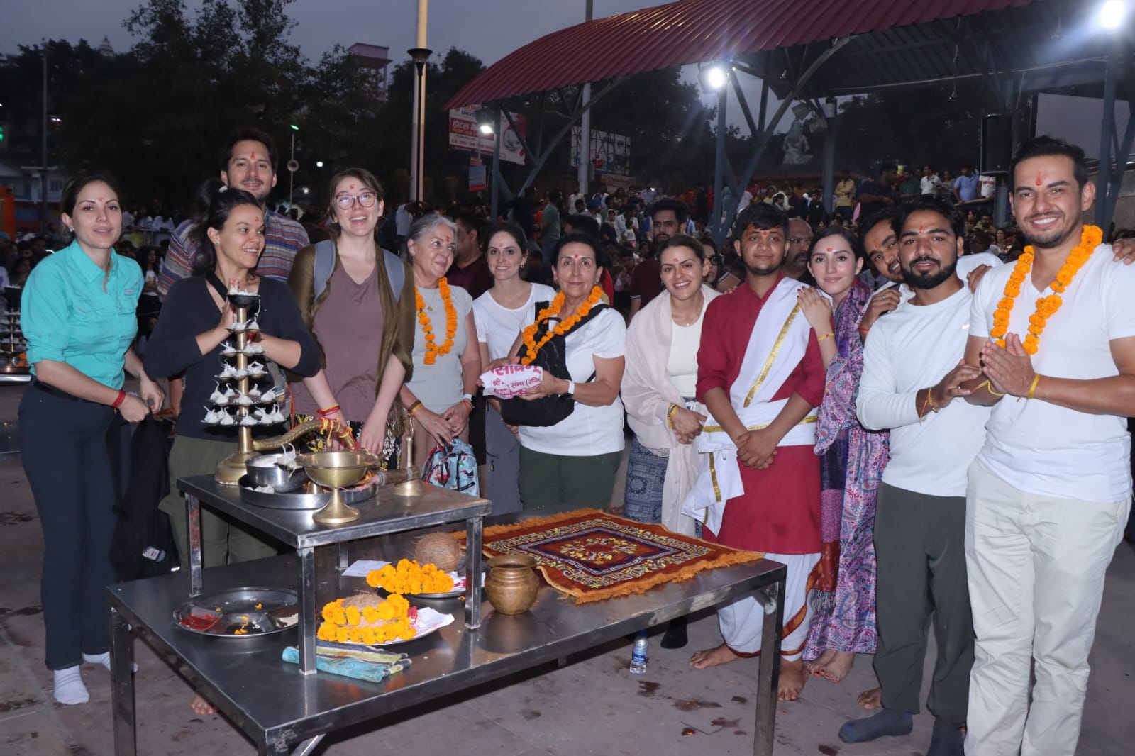 The group gathered at a crowded temple ceremony at night, wearing marigold garlands