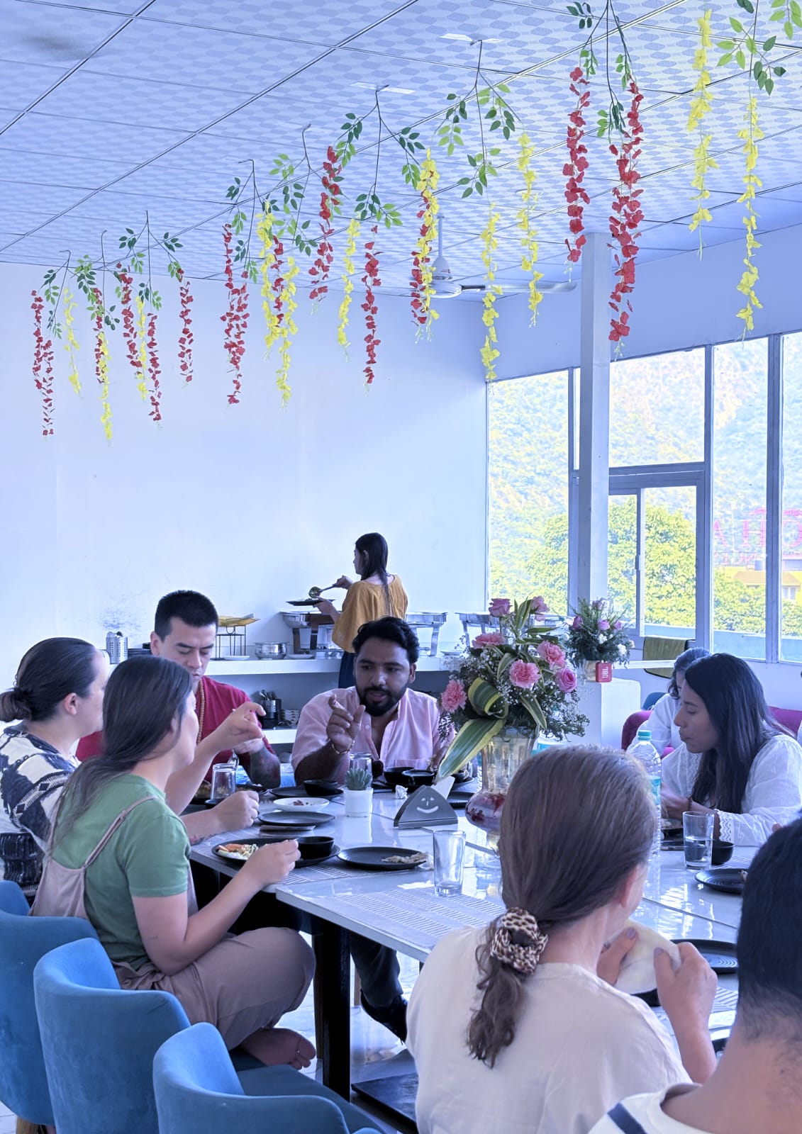 Guests sharing a meal in a dining room decorated with hanging flowers